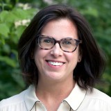 A woman wearing glasses and a white shirt.