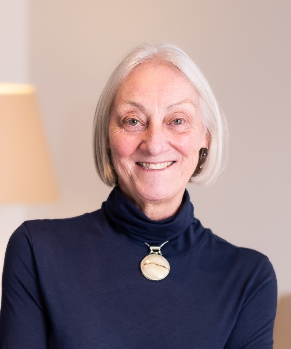 A woman in a blue turtle neck shirt smiling.