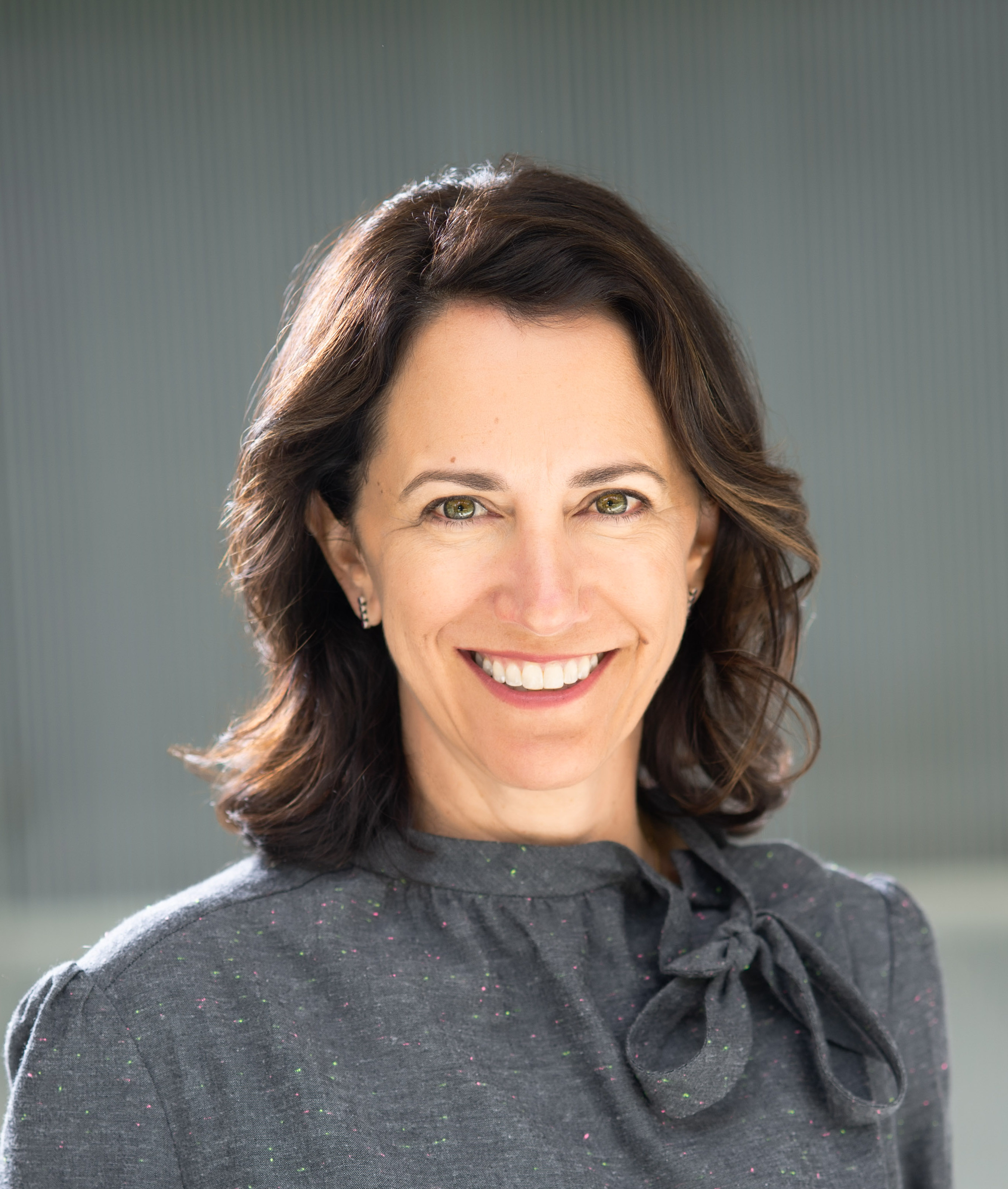 A smiling woman in a gray shirt.