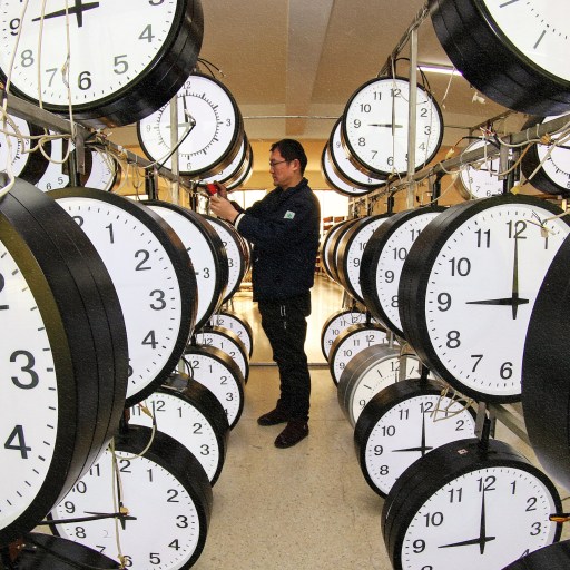 A man surrounded by clocks in a room.