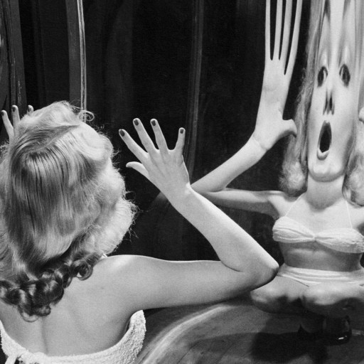 A woman is looking at herself in a mirror.