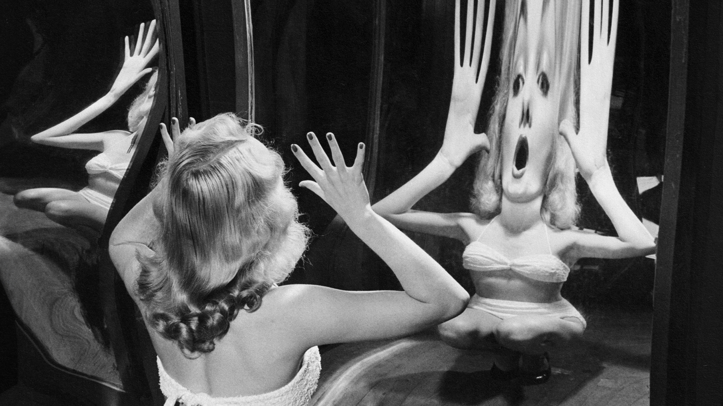 A woman is looking at herself in a mirror.