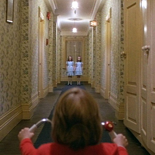 A girl is walking down a hallway in a red shirt, feeling fear.