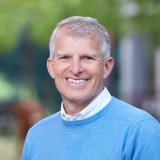 A smiling man in a blue sweater.