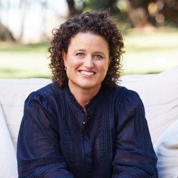 A woman sitting on a couch with curly hair.