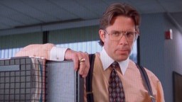 A man in a tie and suspends holding a crate.