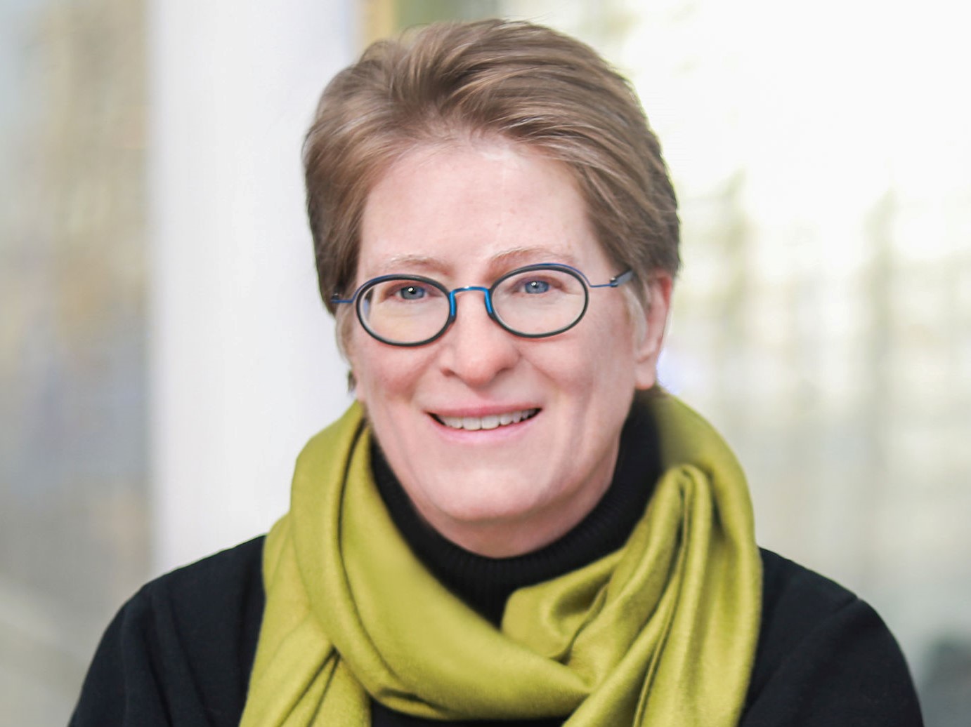 A woman wearing glasses and a green scarf.