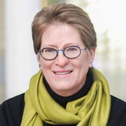 A woman wearing glasses and a green scarf.