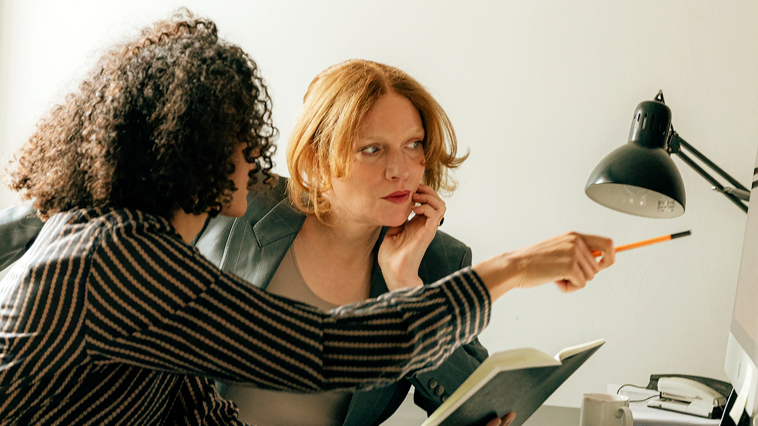 Two women demonstrating authentic leadership while conversing at a desk.