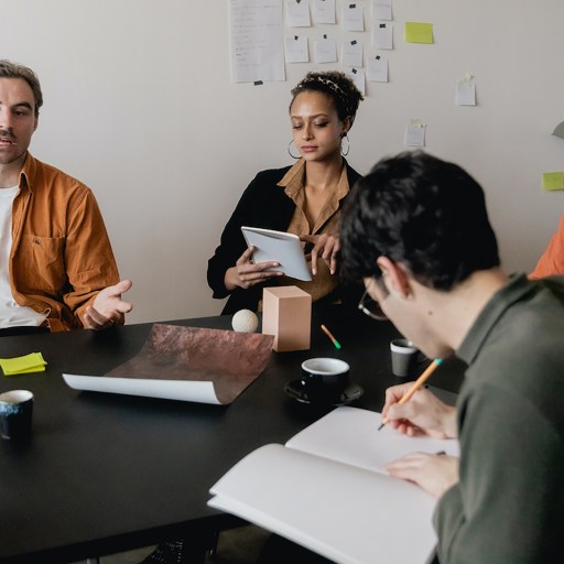 A group of people utilizing effective communication skills sitting around a table in a meeting.