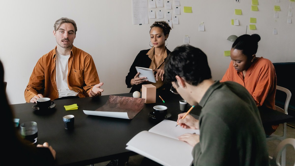 A group of people utilizing effective communication skills sitting around a table in a meeting.