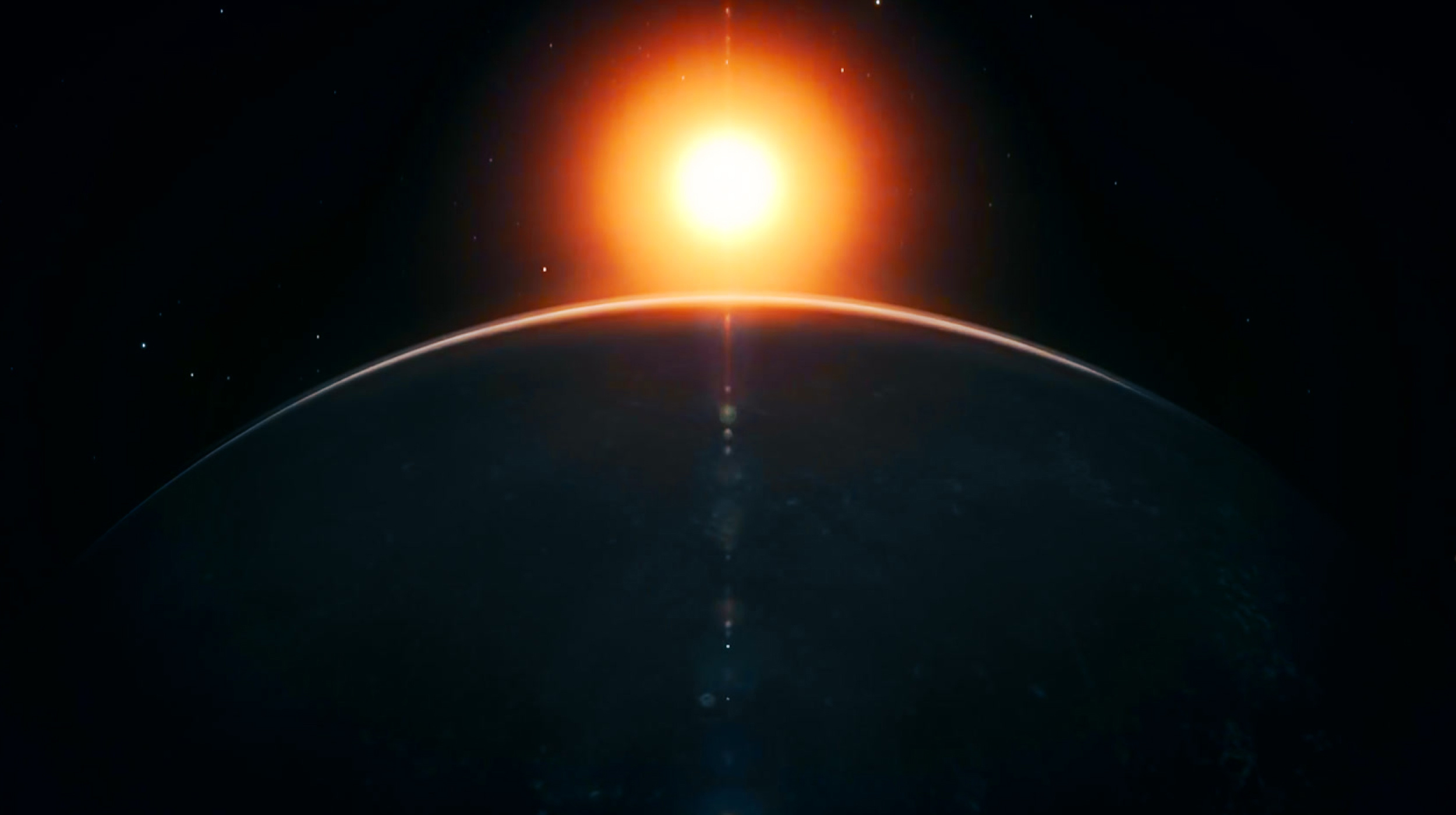 A bright sun rises over the curved horizon of a dark planet in space, with a faint glow outlining the planet’s edge against a starry background.