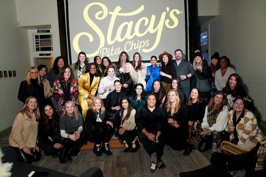 A group of women posing for a photo in front of a large screen.