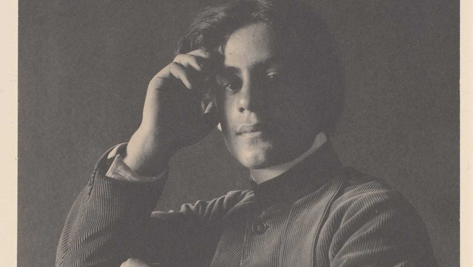 A black and white photo of a man with his hand on his head.