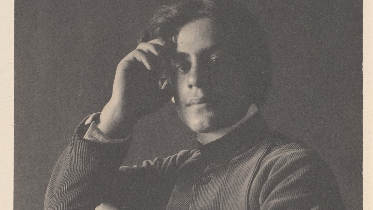 A black and white photo of a man with his hand on his head.