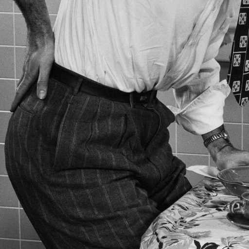 A man sitting at a table with a cup of tea, experiencing chronic pain.