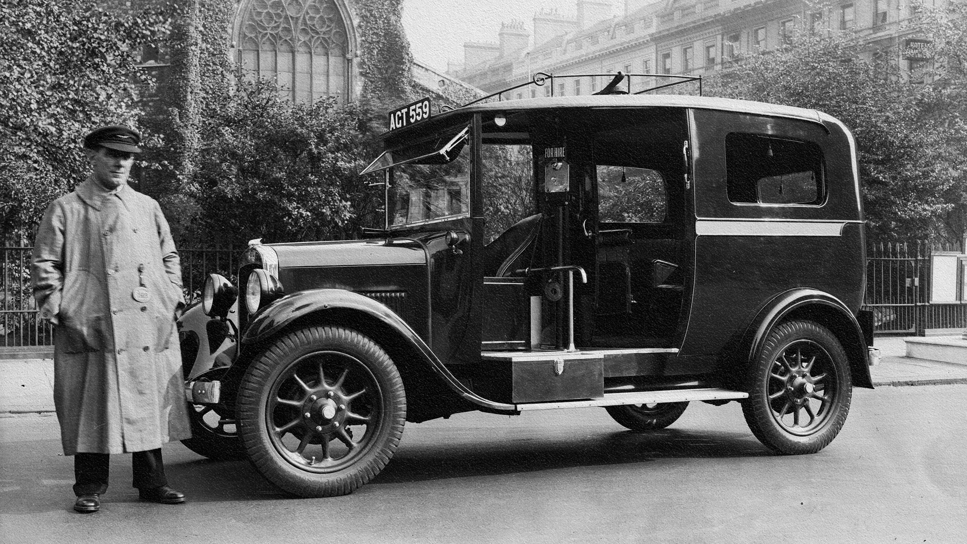 An old photo of a man standing next to an old car showcasing adaptive plasticity.