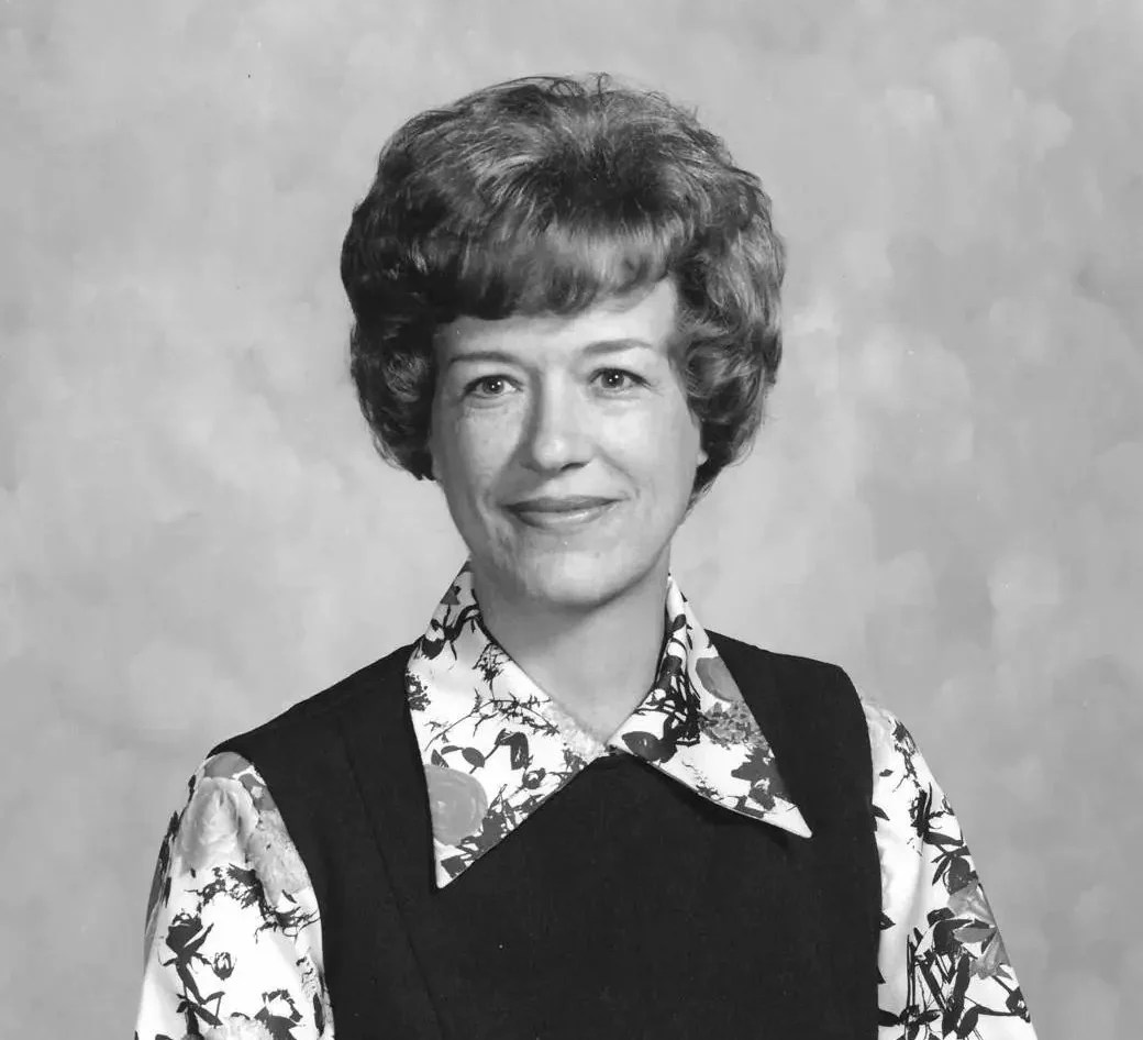 A black and white photo of a woman in a floral dress.