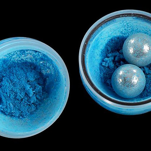 Two blue powders undergoing mechanochemistry in a bowl on a black background.