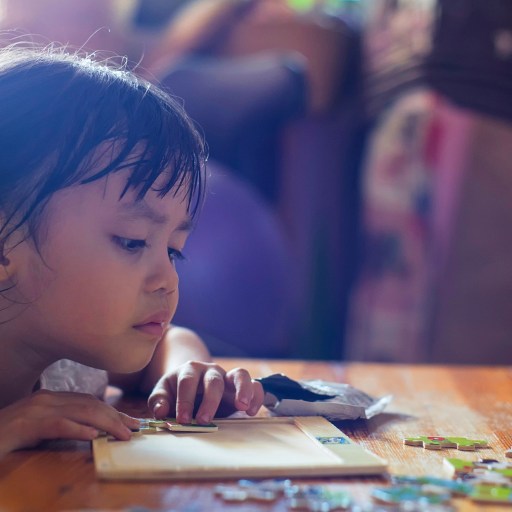 A child happily engaged in solving a large puzzle.
