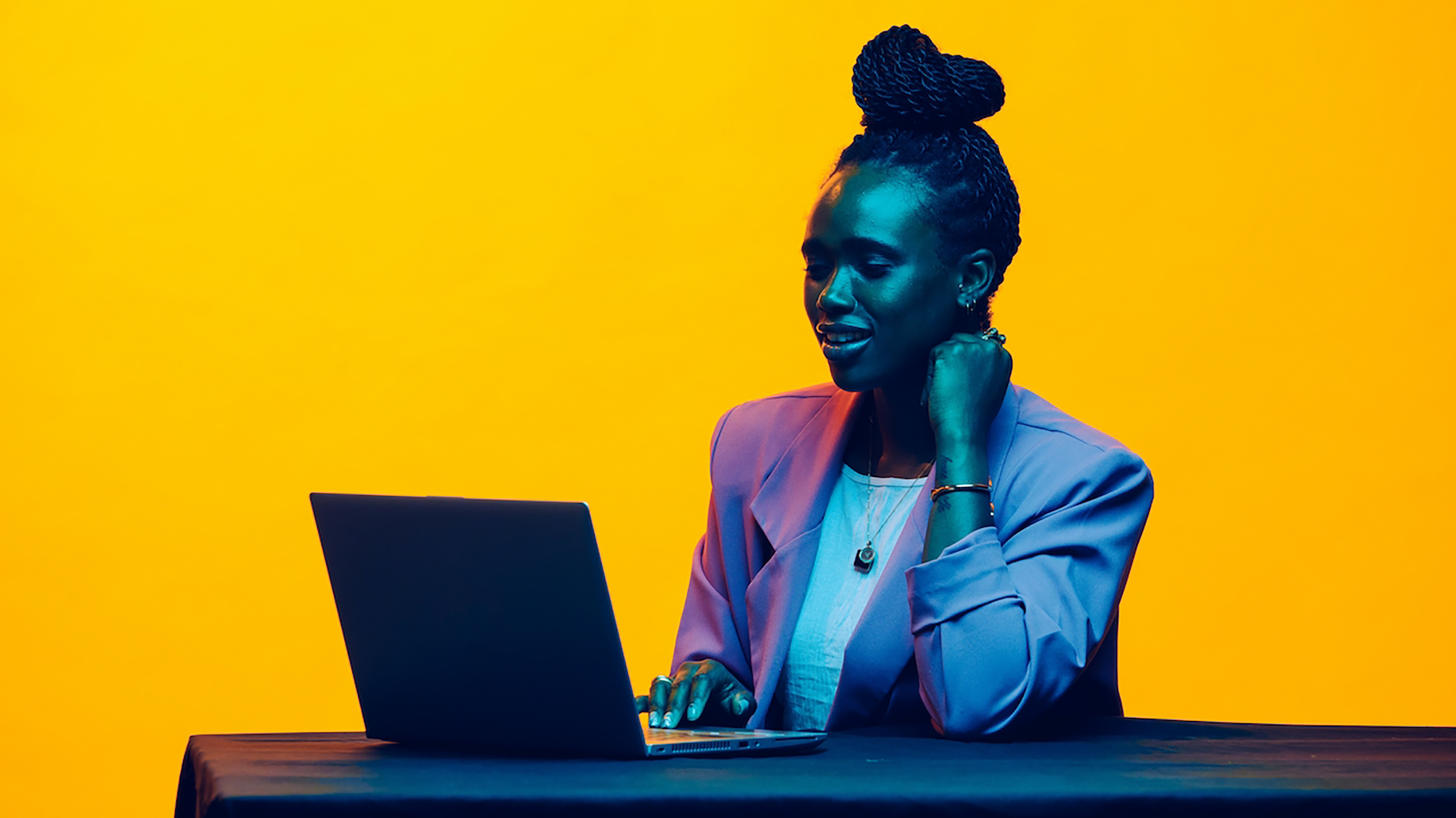 A woman eagerly listening to feedback while sitting at a table with a laptop.