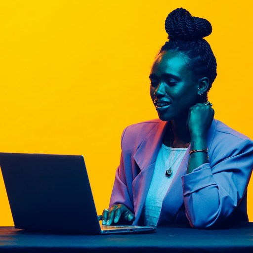 A woman eagerly listening to feedback while sitting at a table with a laptop.
