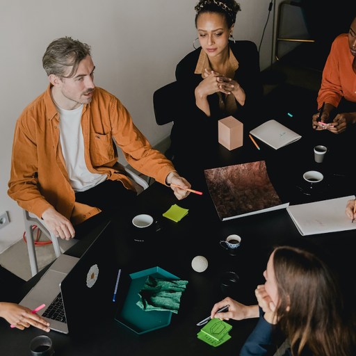 A group of people sitting around a table in a conference room, strategizing on how to retain talent.