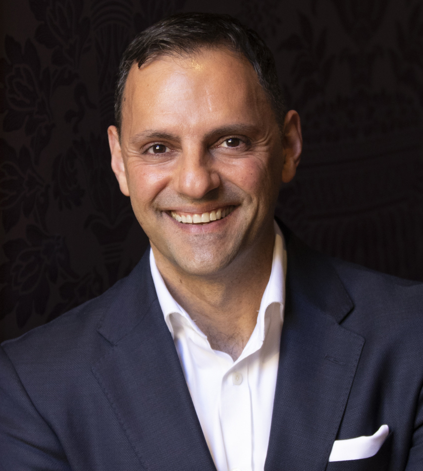 A man in a suit smiling for the camera.