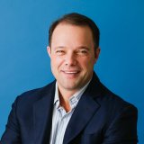 A man in a blue shirt is smiling.