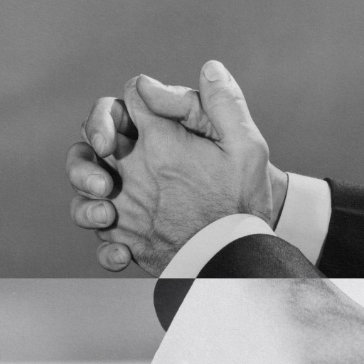 A humble black and white photo of a man with his hands clasped.