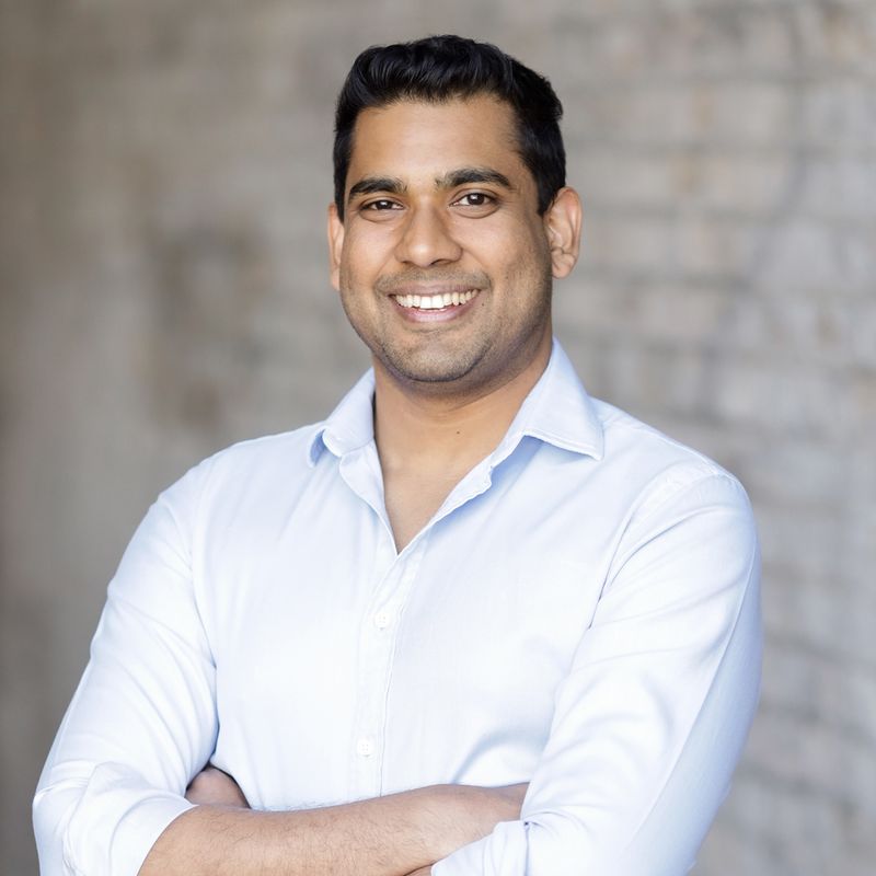 A man with his arms crossed in front of a brick wall.
