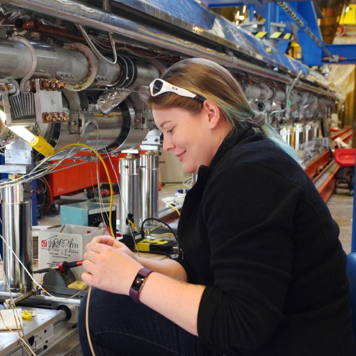 A woman operating an x-ray laser machine in a factory.