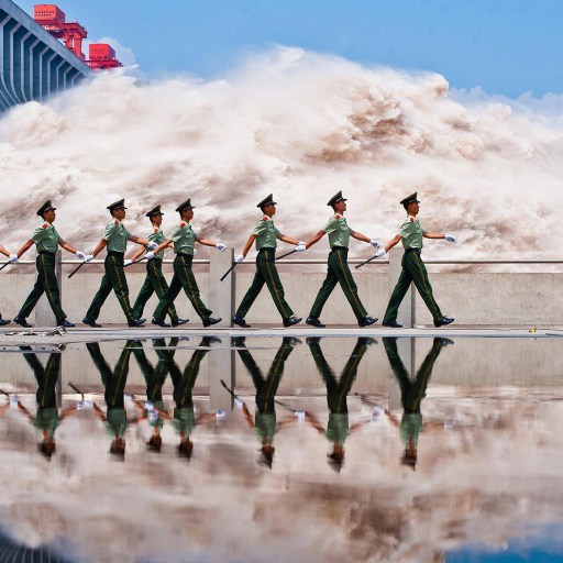 A group of soldiers standing in front of a large wave at Banqiao Dam.