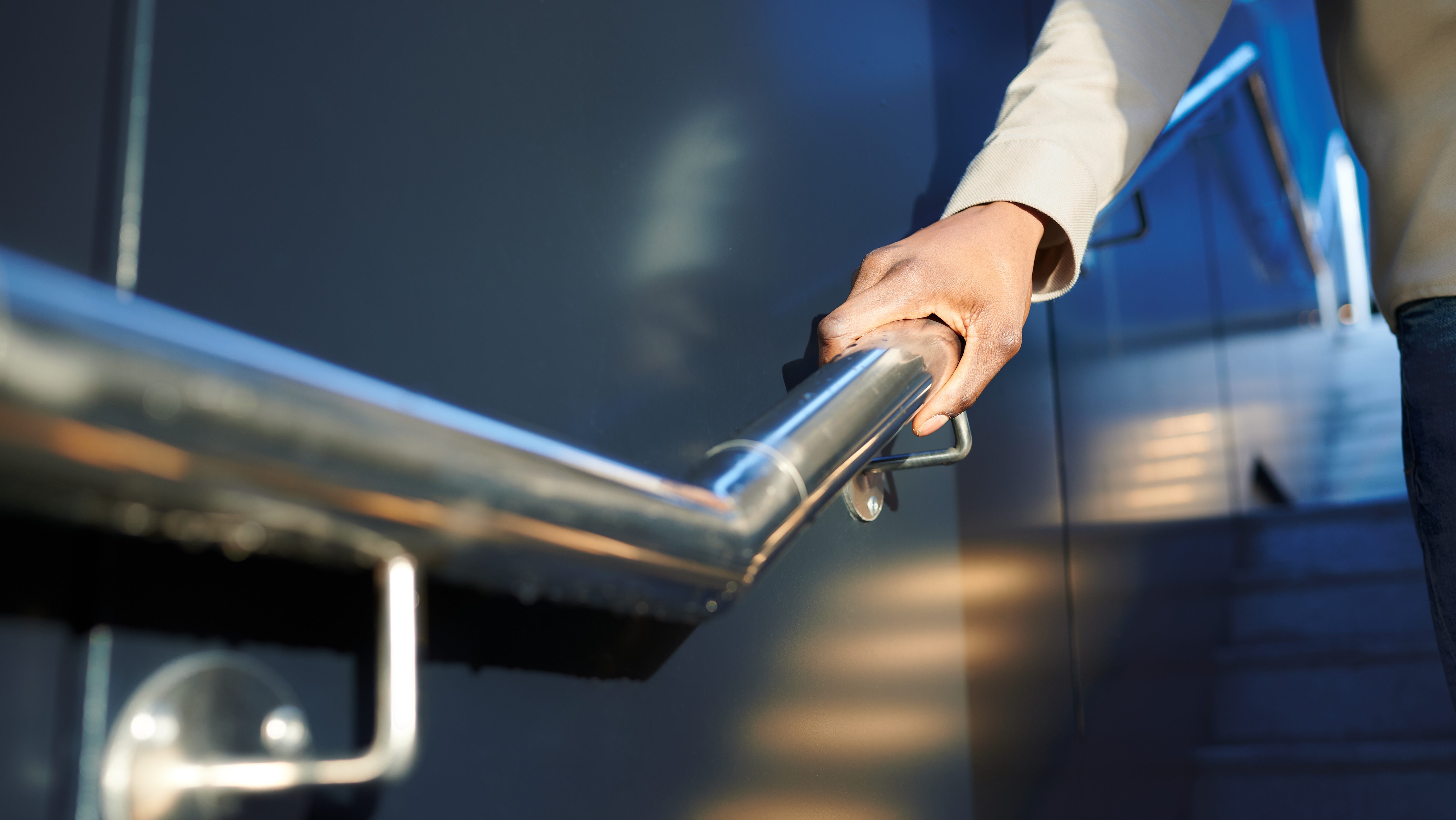 A person holding a stair handrail.