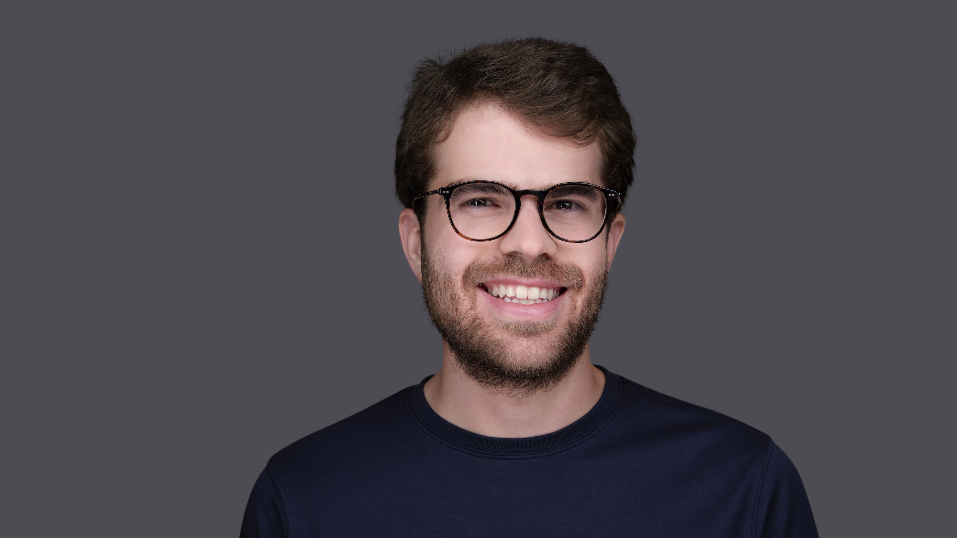 A man with glasses is smiling for the camera, showcasing his ability to operate at all levels.