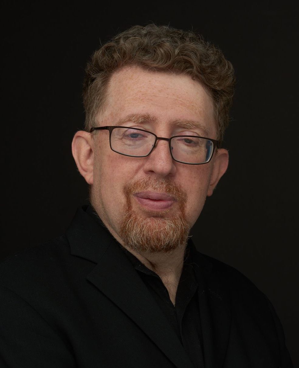 A man with glasses and a beard is posing for a photo.