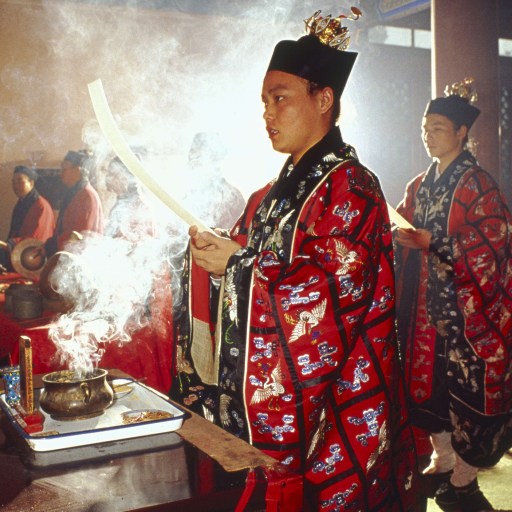 A man in a Chinese costume is holding a candle, exemplifying the essence of Taoism.