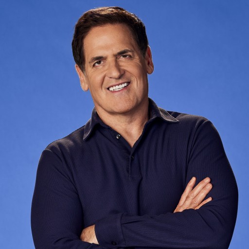 A successful man standing with his arms crossed in front of a vibrant blue background.
