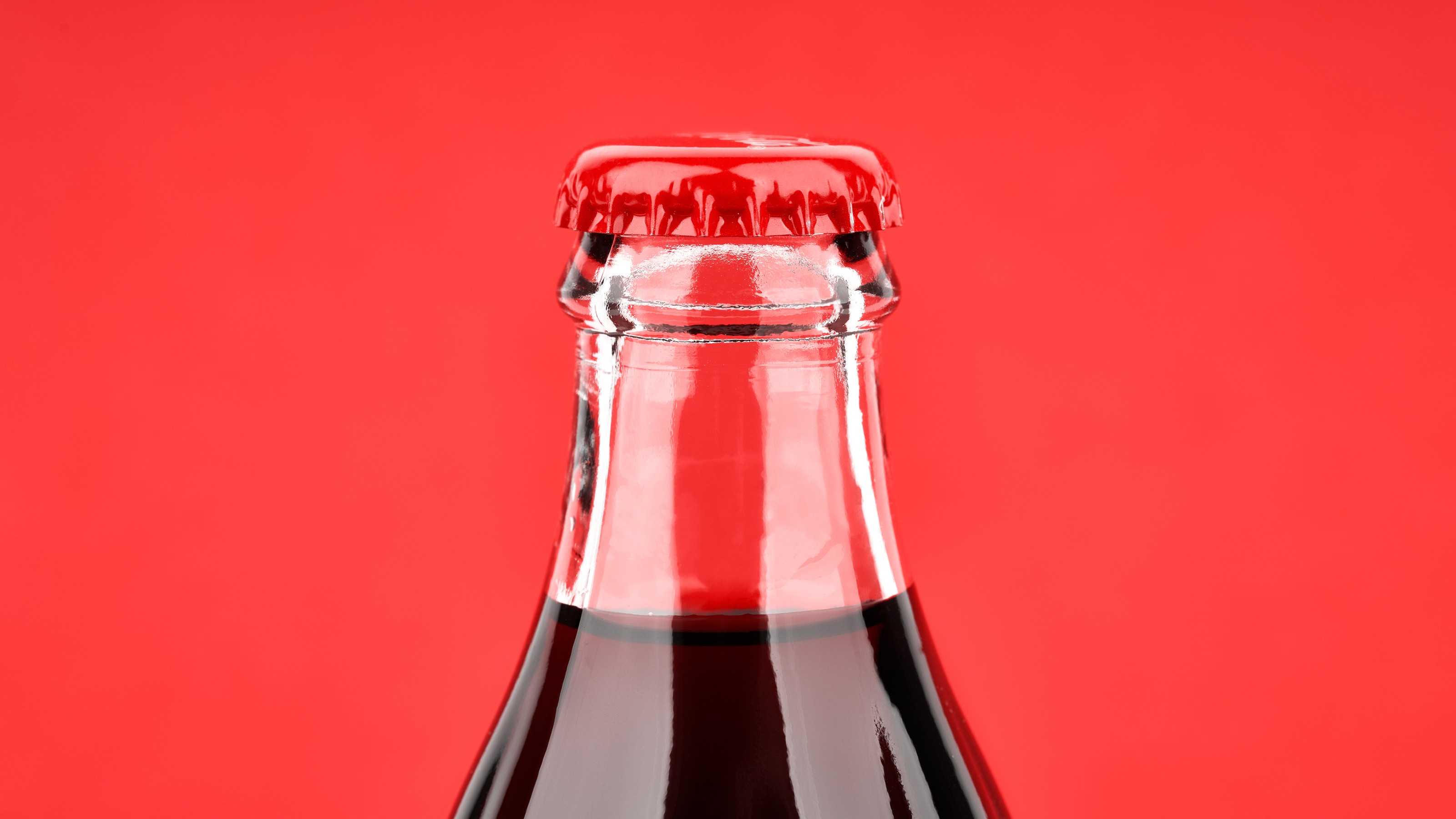 A bottle of Coca Cola on a red background.