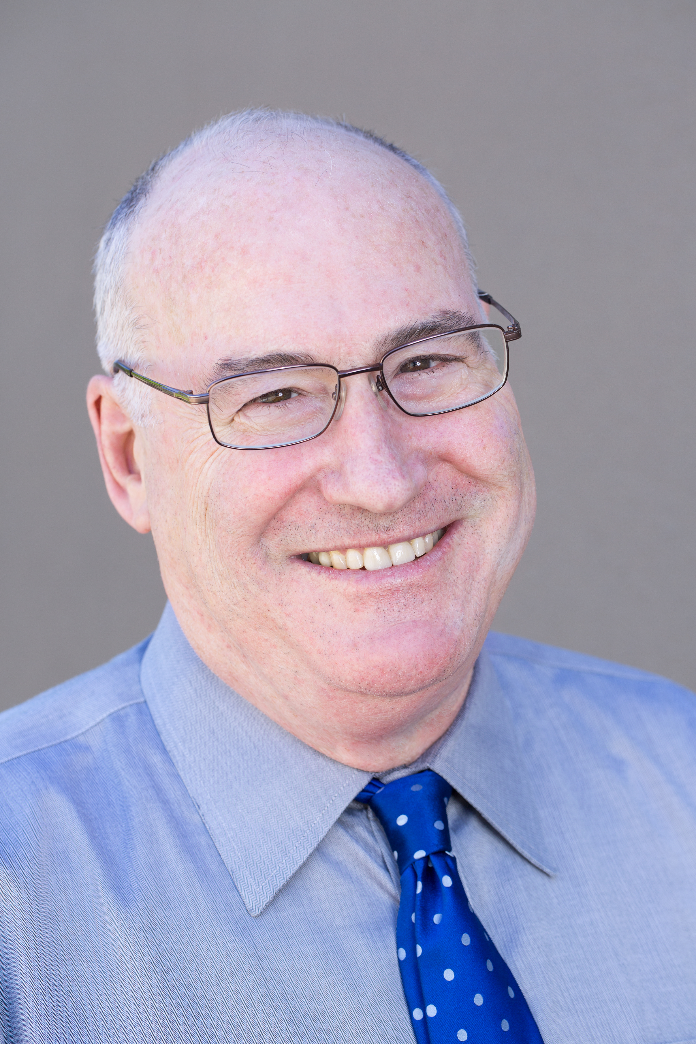 A man wearing glasses and a blue tie.