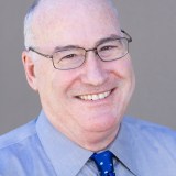 A man wearing glasses and a blue tie.