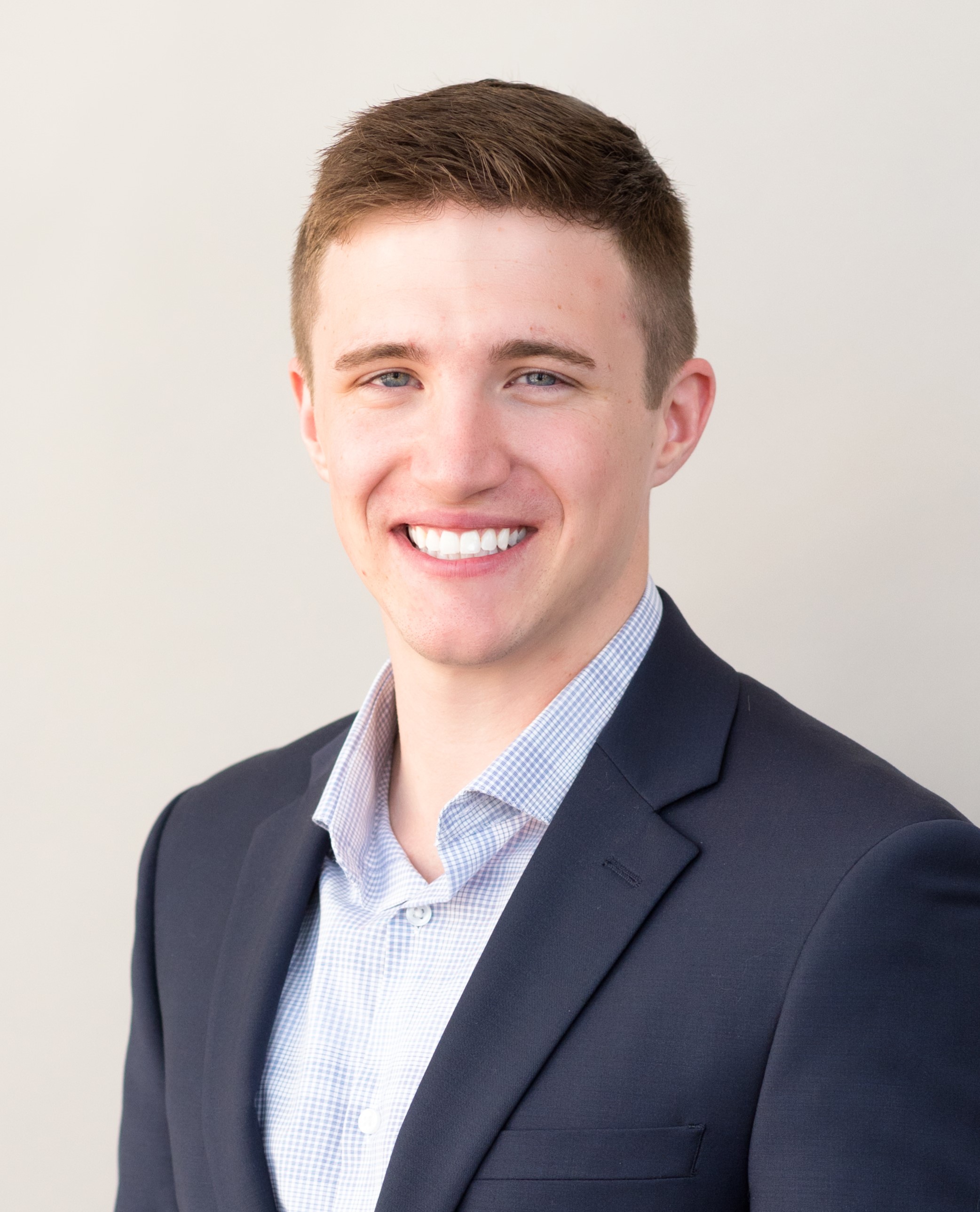 A young man in a suit smiles for the camera.
