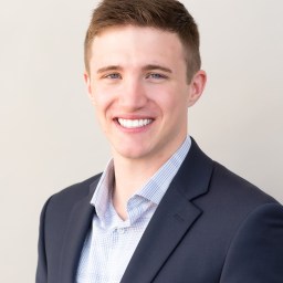 A young man in a suit smiles for the camera.