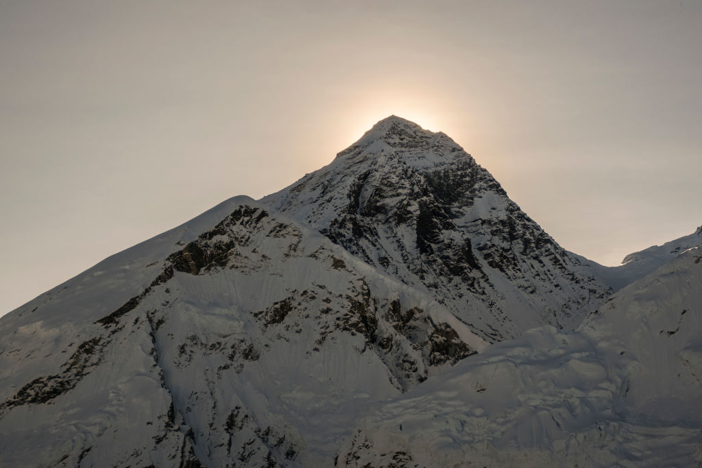 The sun is shining on a snow covered mountain.