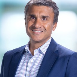 A man in a blue suit smiling for the camera.