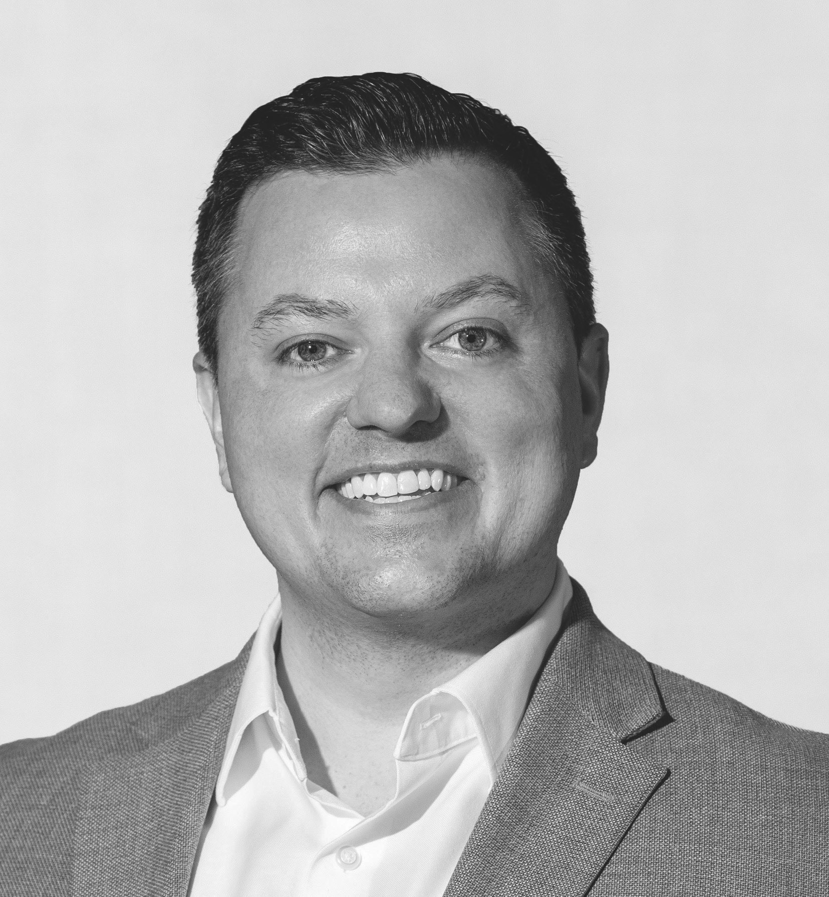 A black and white photo of a man smiling.
