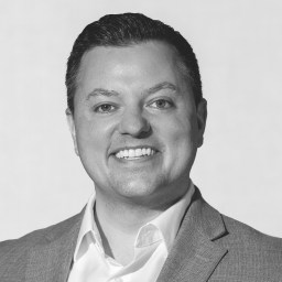 A black and white photo of a man smiling.