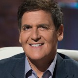 A smiling man in a suit sitting on a chair.