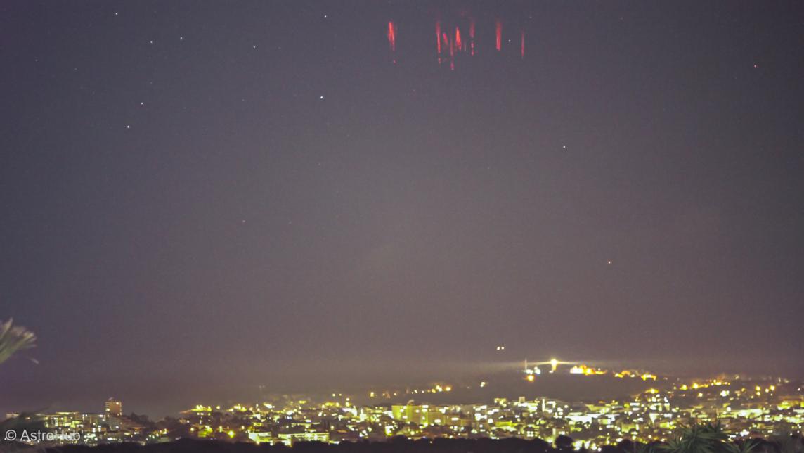 A red light in the sky over a city at night.