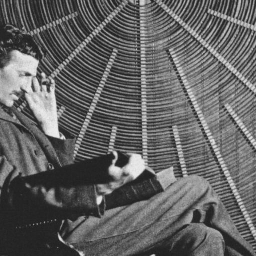 Tesla in a suit sitting in a chair.